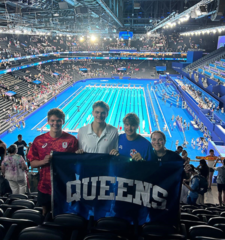 Students at Olympic pool holding a Queens flag