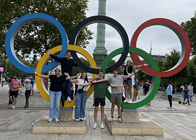 Queens students in front of Olympic rings statue